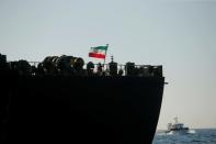 A crew member raises the Iranian flag at Iranian oil tanker Adrian Darya 1, before named as Grace 1, as it sits anchored after the Supreme Court of the British territory lifted its detention order, in the Strait of Gibraltar