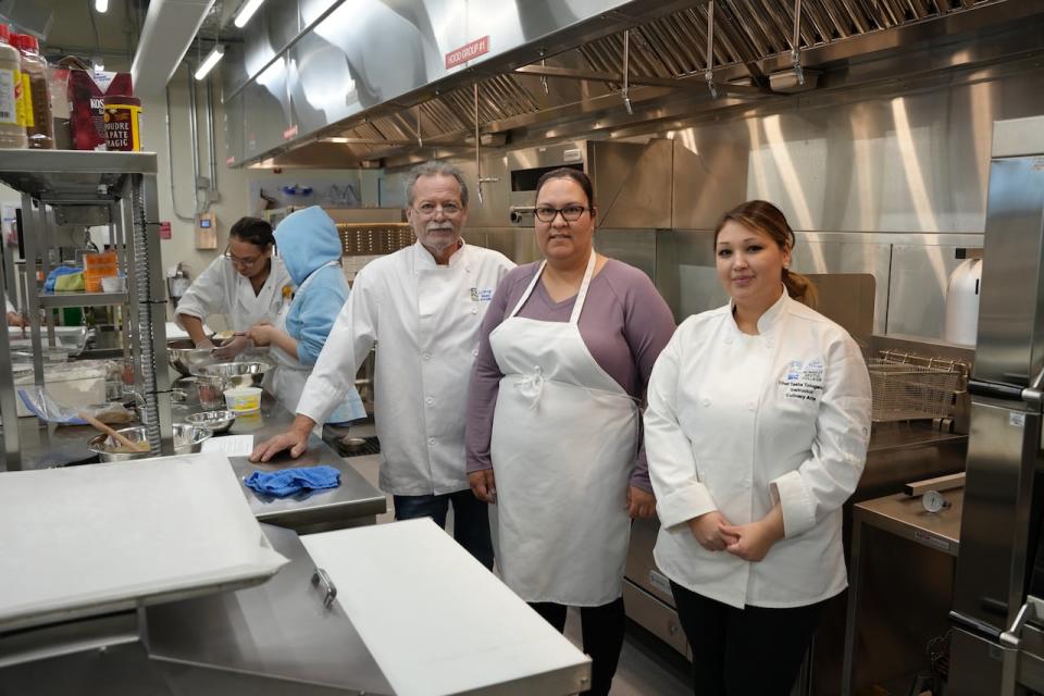 Lead instructor Andy Poisson, third from the left, stands with student Michele Vandenbrink, at centre, and junior instructor Tasha Tologanak in the culinary arts kitchen.