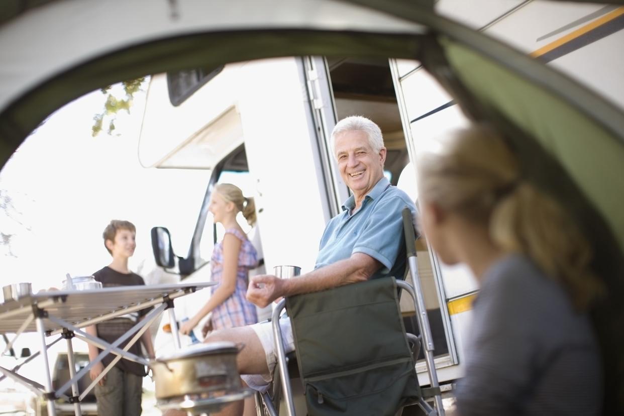 family sitting outside of rv with wife in the tent