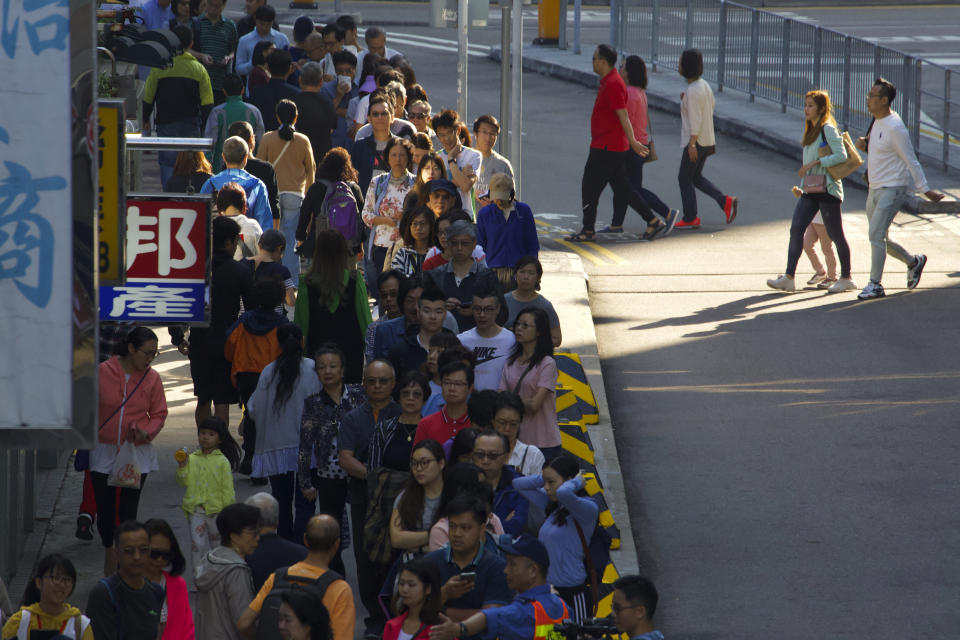 People line up to vote outside of a polling place in Hong Kong, Sunday, Nov. 24, 2019. Long lines formed outside Hong Kong polling stations Sunday in elections that have become a barometer of public support for anti-government protests now in their sixth month. (AP Photo/Ng Han Guan)