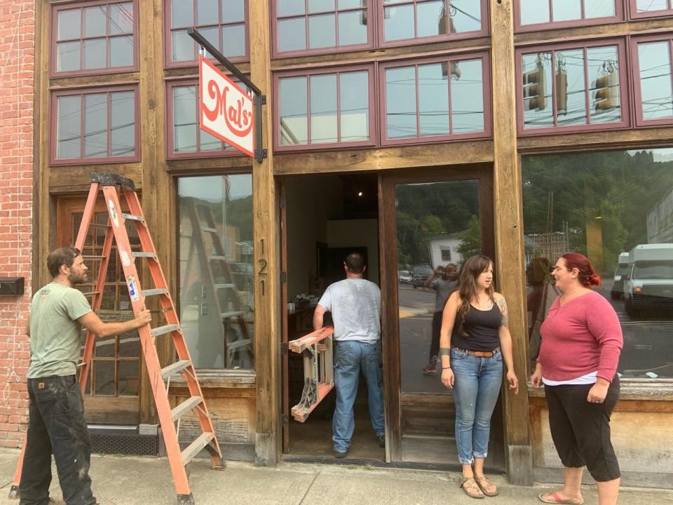 Members of Every Angle Construction prepare ladders beside Mallory McCoy, second from right, and Sweet Monkey owner Hollie West Aug. 9.