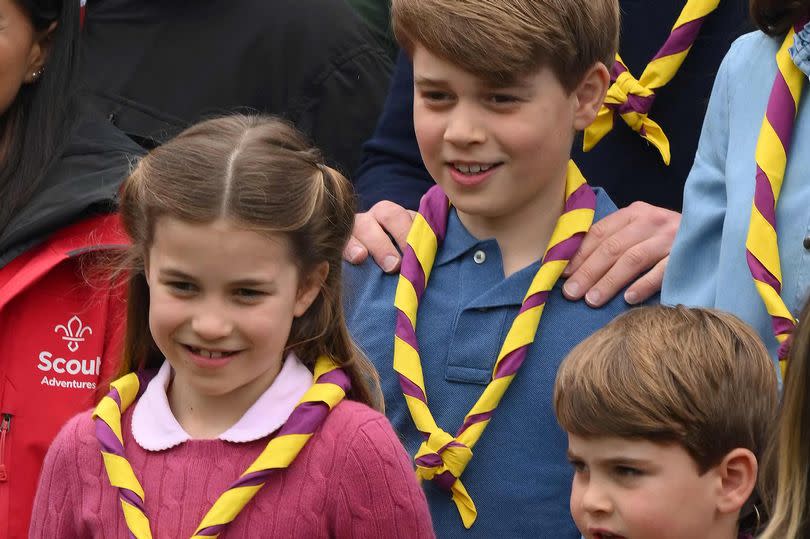 Britain's Prince George of Wales (C), Britain's Prince Louis of Wales (R) and Britain's Princess Charlotte of Wales (L) pose for a group picture with volunteers who are taking part in the Big Help Out, during a visit to the 3rd Upton Scouts Hut in Slough, west of London on May 8, 2023, where the family helped to renovate and improve the building.