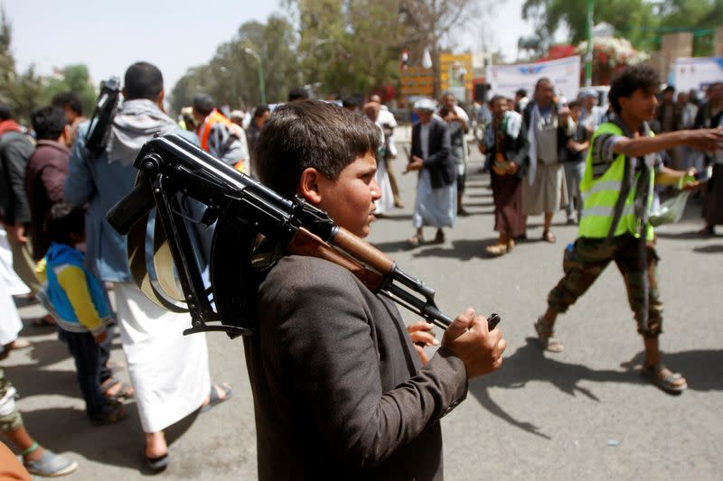 FILE PHOTO: A boy carries a weapon as he and Houthi supporters are seen during a gathering in Sanaa