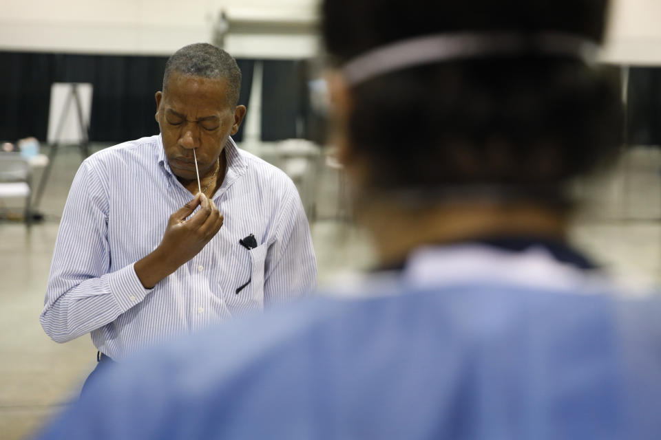 Clark County Commission Vice Chairman Lawrence Weekly swabs his nose while giving a coronavirus test to himself during a tour of setup at a temporary coronavirus testing site Monday, Aug. 3, 2020, in Las Vegas. (AP Photo/John Locher)
