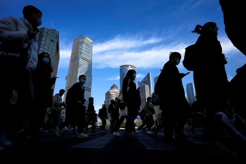 People cross a street near office towers in the Lujiazui financial district, ahead of the National People's Congress (NPC), in Shanghai