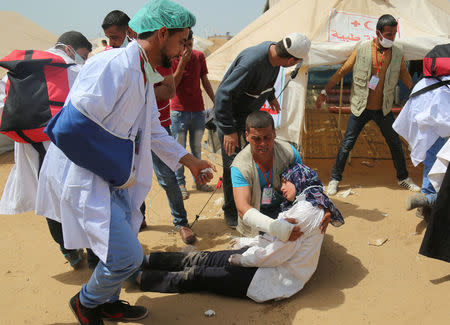 A woman who volunteers with other paramedics reacts to tear gas fired by Israeli troops during a protest where Palestinians demand the right to return to their homeland, at the Israel-Gaza border, in the southern Gaza Strip April 13, 2018. REUTERS/Samar Abo Elouf