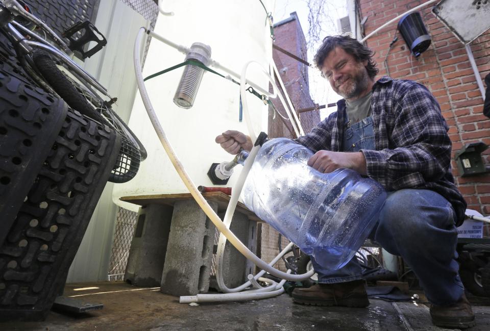 Jonathan Steele, owner of Bluegrass Kitchen, fills a jug with cleaning water in the back of his restaurant in Charleston, W.Va., Tuesday, Jan. 14, 2014. Steele installed a large tank in the back of his restaurant and was able to open his restaurant using bottled water on Sunday. . (AP Photo/Steve Helber)