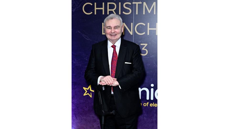 Eamonn Holmes in a black suit with a black cane