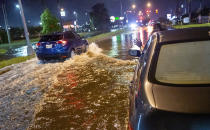 Lamont Pepp, right, waves to a passing motorist to slow down after Pepp's car stalled in high water on Gause Boulevard in Slidell late Friday, June 18, 2021, as a tropical disturbance neared the Louisiana shore. Tropical Storm Claudette has formed Saturday morning along the U.S. Gulf Coast, bringing heavy rains and flooding to coastal states including Louisiana, Mississippi and Alabama. (Scott Threlkeld/The Advocate via AP)