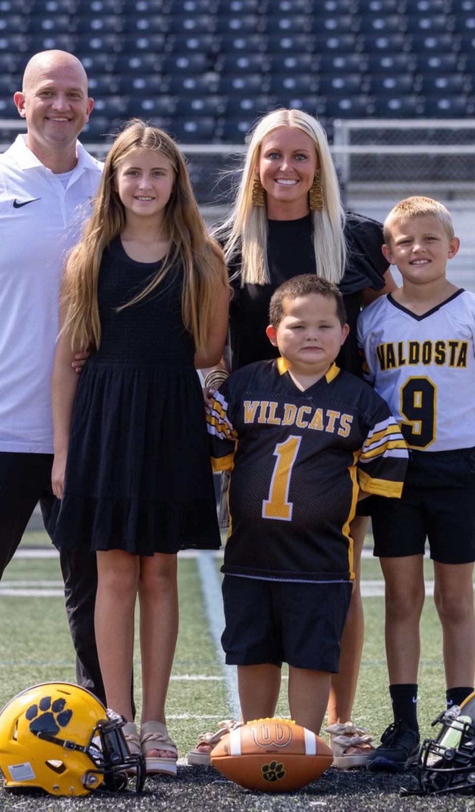 Coach Tyler Wynn with his family on the sidelines of Valdosta High School in Georgia, fall 2023: daughter Austyn-Claire, 11; wife Brittany; son Dax, 5; and son Cam, 10.