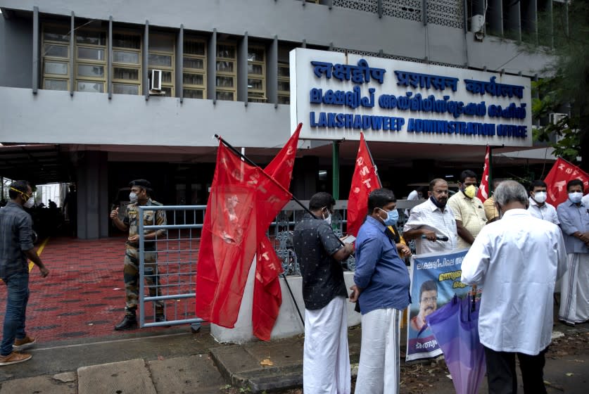 A security person checks on a visitor, left as activists of Centre of Indian Trade Unions (CITU) gather for a protest outside the Lakshadweep administration office in Kochi, Kerala state, India, Tuesday, June 15, 2021. A dozen activists of the CITU staged a peaceful protest here Tuesday expressing solidarity with the inhabitants of the archipelago who have been protesting against the reforms of a new administrator appointed by the Indian government. (AP Photo/R S Iyer)