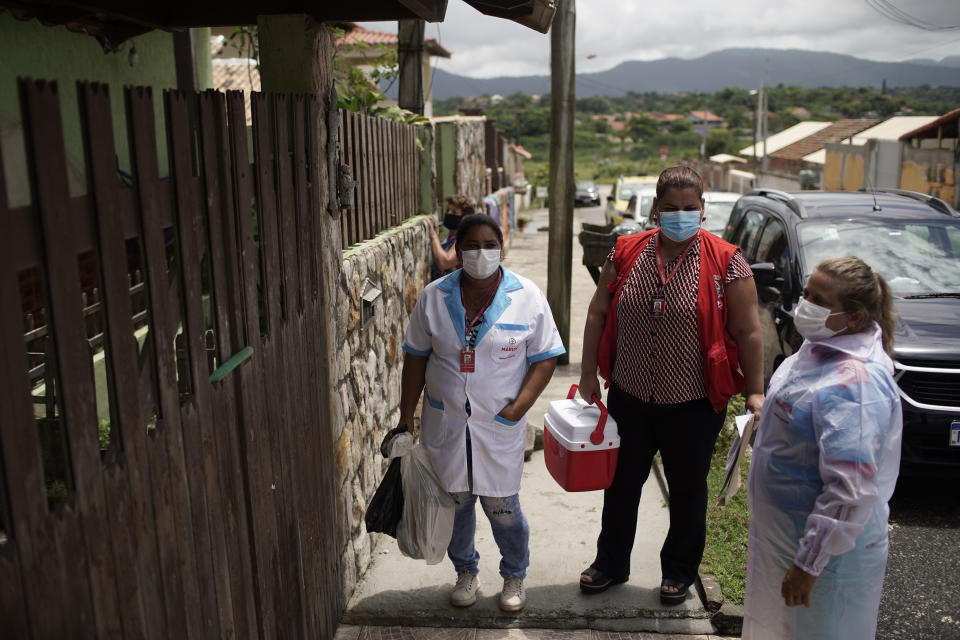 Health workers carry doses of China's Sinovac Corona Vac vaccine for COVID-19 to give seniors in their homes as part of a vaccination program for the house-bound elderly in Marica, Rio de Janeiro state, Brazil, Monday, Feb. 22, 2021. (AP Photo/Silvia Izquierdo)