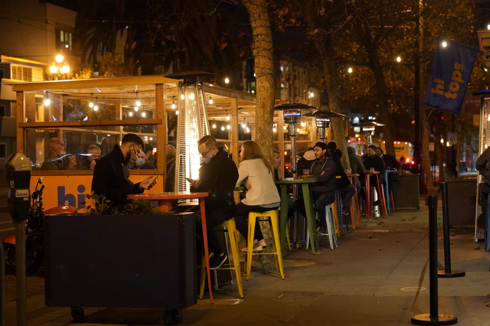 People sit in an outdoor dining area on Market Street amid the coronavirus outbreak in San Francisco, Tuesday, Nov. 24, 2020. (AP Photo/Jeff Chiu)