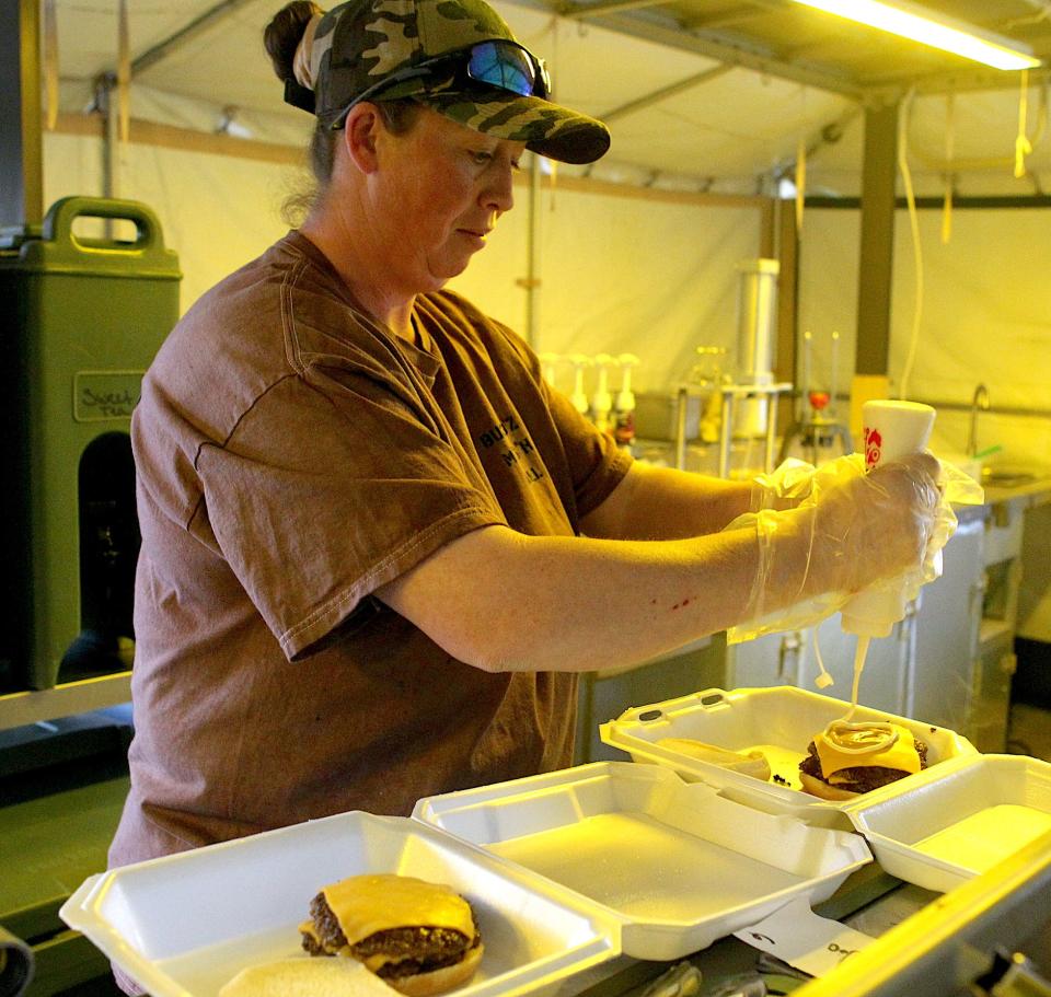 Jeni Beasley dresses a smash burger at Busy B'z Mash Hall at the Eclipse Over Lawrence County celebration Friday, April 5, 2024, at the Lawrence County Fairgrounds.