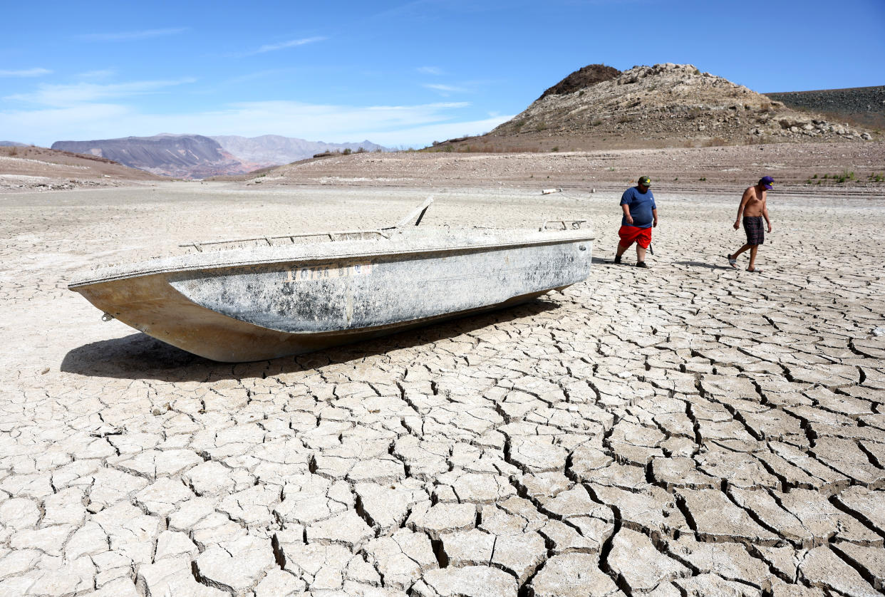 Local residents walk on a section of dry lake bed along drought-stricken Lake Mead, Nev.