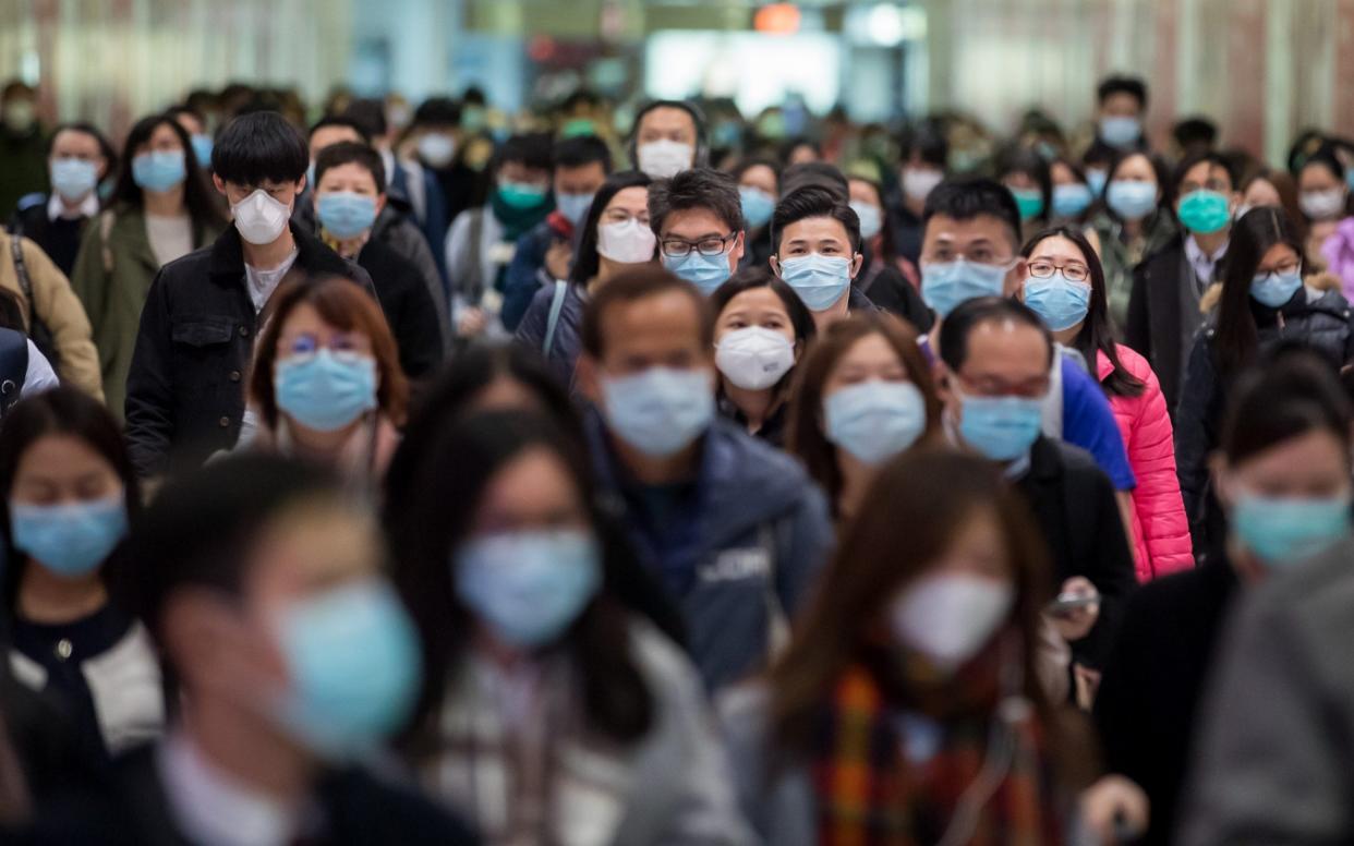 Commuters wearing protective masks walk through Hong Kong Station - Bloomberg