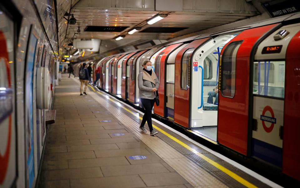 A woman wearing PPE (personal protective equipment), including a face mask as a precautionary measure against COVID-19, walks along the platform alongside a London Underground Tube train, in the morning rush hour on May 11, 2020, as life in Britain continues during the nationwide lockdown due to the novel coronavirus pandemic. - British Prime Minister Boris Johnson on May 10 announced a phased plan to ease a nationwide coronavirus lockdown, with schools and shops to begin opening from June 1 -- as long as infection rates stay low. (Photo by Tolga Akmen / AFP) (Photo by TOLGA AKMEN/AFP via Getty Images)