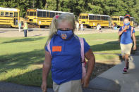 Following direction, McCartney Moulds, 6, a second-grader, distances herself from a fellow student as she walks to class with full mask following her bus commute, to the Newton County Elementary School in Decatur, Miss., Monday, Aug. 3, 2020. Thousands of students across the nation are set to resume in-person school Monday for the first time since March. Parents are having to balance the children's need for socialization and instruction that school provides, with the reality that the U.S. death toll from the coronavirus has hit about 155,000 and cases are rising in numerous places. (Janine Vincent/Newton County Schools via AP)