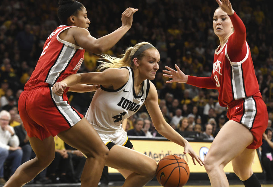 Iowa guard Kylie Feuerbach (4) drives between Ohio State guard/forward Taylor Thierry (2) and forward Rebeka Mikulasikova, right, during the second half of an NCAA college basketball game, Sunday, March 3, 2024, in Iowa City, Iowa. (AP Photo/Cliff Jette)