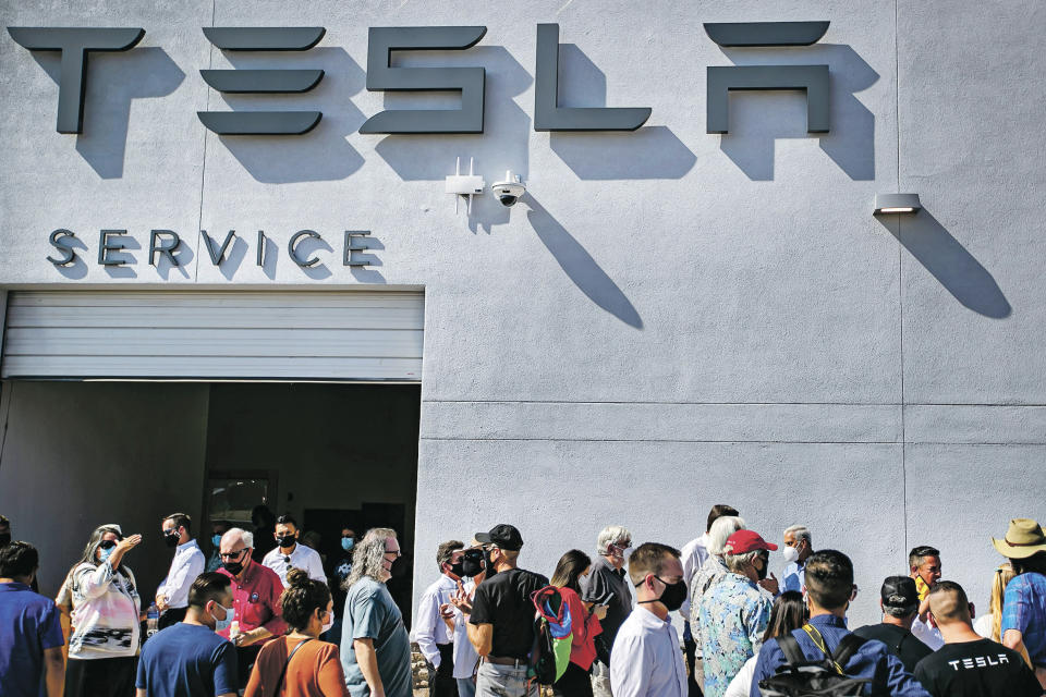 Tesla owners, Tesla employees and local political leaders gather at the service bay doors during an event on Sept. 9, 2021, to celebrate a partnership between Tesla and the Nambé Pueblo after the electric car company repurposed a defunct casino into a sales, service and delivery center near Santa Fe, N.M. Tesla has opened a store on tribal land in New Mexico, sidestepping car dealership laws that prohibit car companies from selling directly to customers. (Jim Weber/Santa Fe New Mexican via AP)