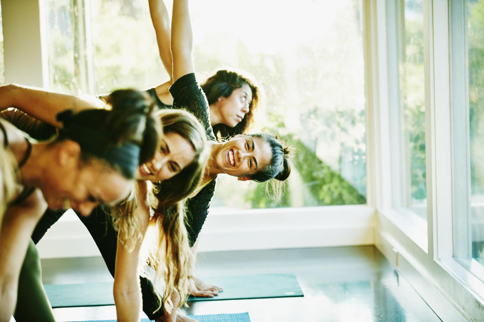 Friends laughing doing yoga classes together. (Getty Images)