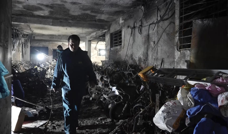 A security officer walks past burned vehicles in an apartment building that was caught fire in Hanoi, Vietnam Thursday, Sept. 14, 2023. A fire broke just before midnight Tuesday in the apartment building that killed scores of people. (AP Photo/Hau Dinh)