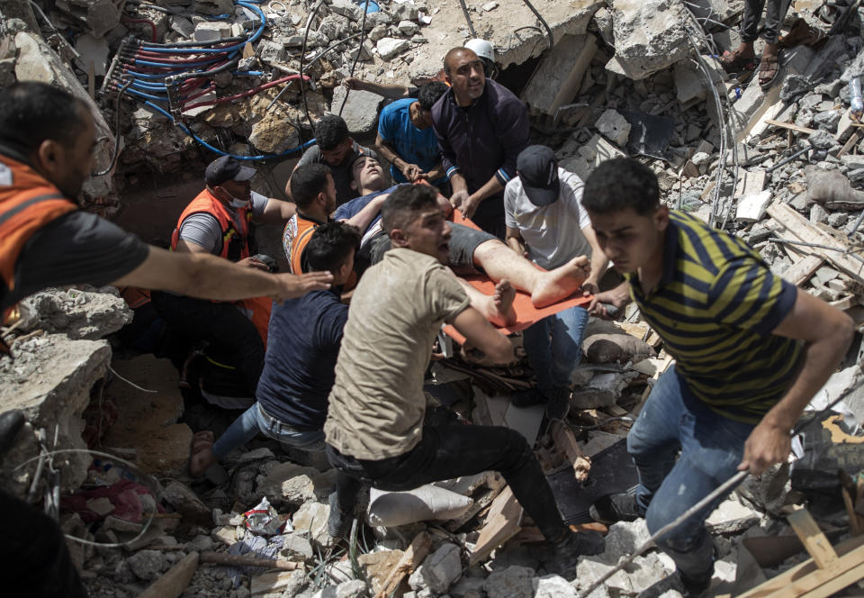 FILE - In this May 16, 2021, file photo, Palestinian rescue a survivor from under the rubble of a destroyed residential building following deadly Israeli airstrikes in Gaza City. Human Rights Watch on Tuesday, July 27, 2021, accused the Israeli military of carrying attacks that "apparently amount to war crimes" during an 11-day war against the Hamas militant group in May. (AP Photo/Khalil Hamra, File)