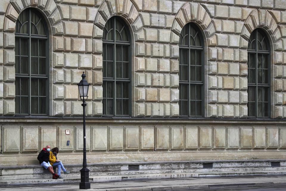 People wear a face masks as they sit on stairs in downtown in Munich, Germany, Friday, Oct. 30, 2020. In Munich city center masks are mandatory to avoid the spread of the coronavirus and the COVID-19 disease. (AP Photo/Matthias Schrader)