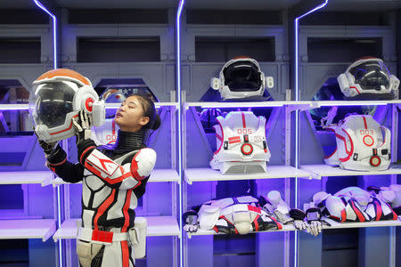 A staff member demonstrates how she puts on the helmet of a mock space suit at the C-Space Project Mars simulation base in the Gobi Desert outside Jinchang, Gansu Province, China, April 17, 2019. REUTERS/Thomas Peter