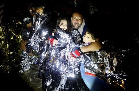 A Syrian refugee tries to keep his children warm after being rescued by Greek fishermen on the Greek island of Lesbos October 19, 2015. REUTERS/Yannis Behrakis