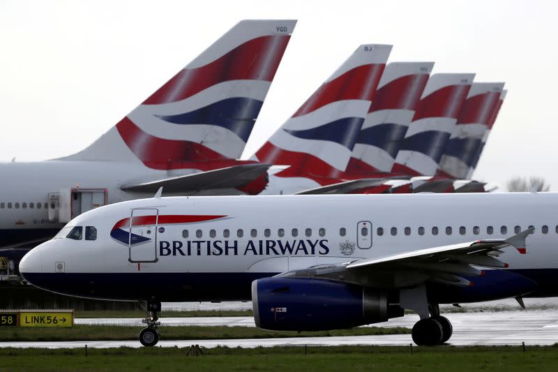 FILE PHOTO: BA plane taxis past tail fins of parked aircraft to runway near Terminal 5 at Heathrow Airport