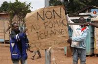 Christian men hold a placard in Bangui December 10, 2013. The French army said it has restored some stability in the capital of Central African Republic after battling gunmen on Monday in an operation to disarm rival Muslim and Christian fighters responsible for killing hundreds since last week. The placard reads: "No to Chad Multinational Force of Central Africa (FOMAC). They are traitors." REUTERS/Emmanuel Braun
