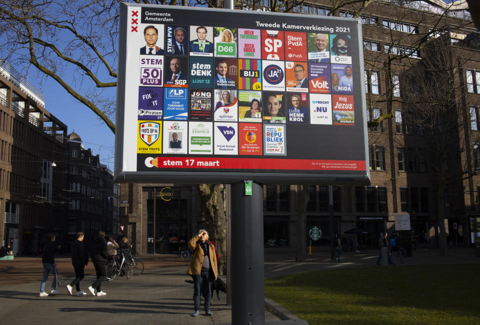 A man shields his eyes from the sun as he looks up at an election billboard with a multitude of political parties in Amsterdam, Netherlands, Saturday, Feb. 27, 2021. After more than a decade in power, a recent scandal that forced him to resign and a year battling the coronavirus, Dutch Prime Minister Mark Rutte's popularity, heightened by his handling of the pandemic, remains high less than a month before a general election. But it is showing signs of eroding along with support for his country's tough COVID-19 lockdown as the vote approaches. (AP Photo/Peter Dejong)