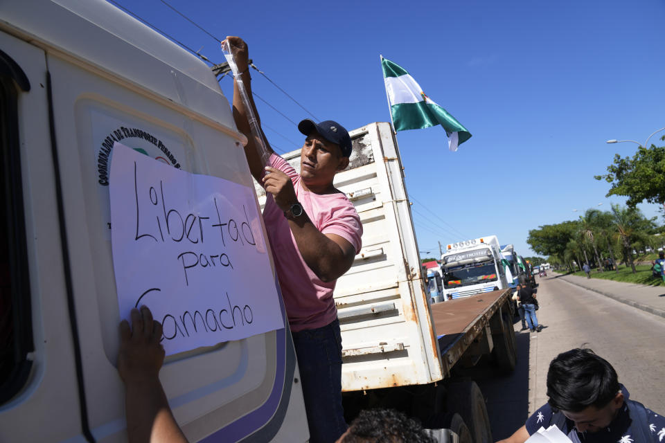 Un conductor de camión pega un cartel pidiendo libertad para Camacho en una caravana de camioneros que reclaman la liberación del detenido líder de la oposición y gobernador de Santa Cruz, Luis Fernando Camacho, en Santa Cruz, Bolivia, el jueves 5 de enero de 2023. La fiscalía envió el 29 de diciembre de 2022 a Camacho a prisión preventiva por cuatro meses mientras enfrenta cargos por terrorismo. (AP Foto/Juan Karita)