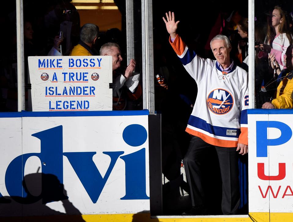 Hockey Hall of Famer and former New York Islander Mike Bossy waves to fans as he is introduced before the NHL hockey game between the Islanders and the Boston Bruins at Nassau Coliseum on Thursday, Jan. 29, 2015, in Uniondale, N.Y. Bossy dropped a ceremonial first puck. Bossy, one of hockey’s most prolific goal-scorers and a star for the New York Islanders during their 1980s dynasty, died Friday, April 15, 2022, after a battle with lung cancer. He was 65. 