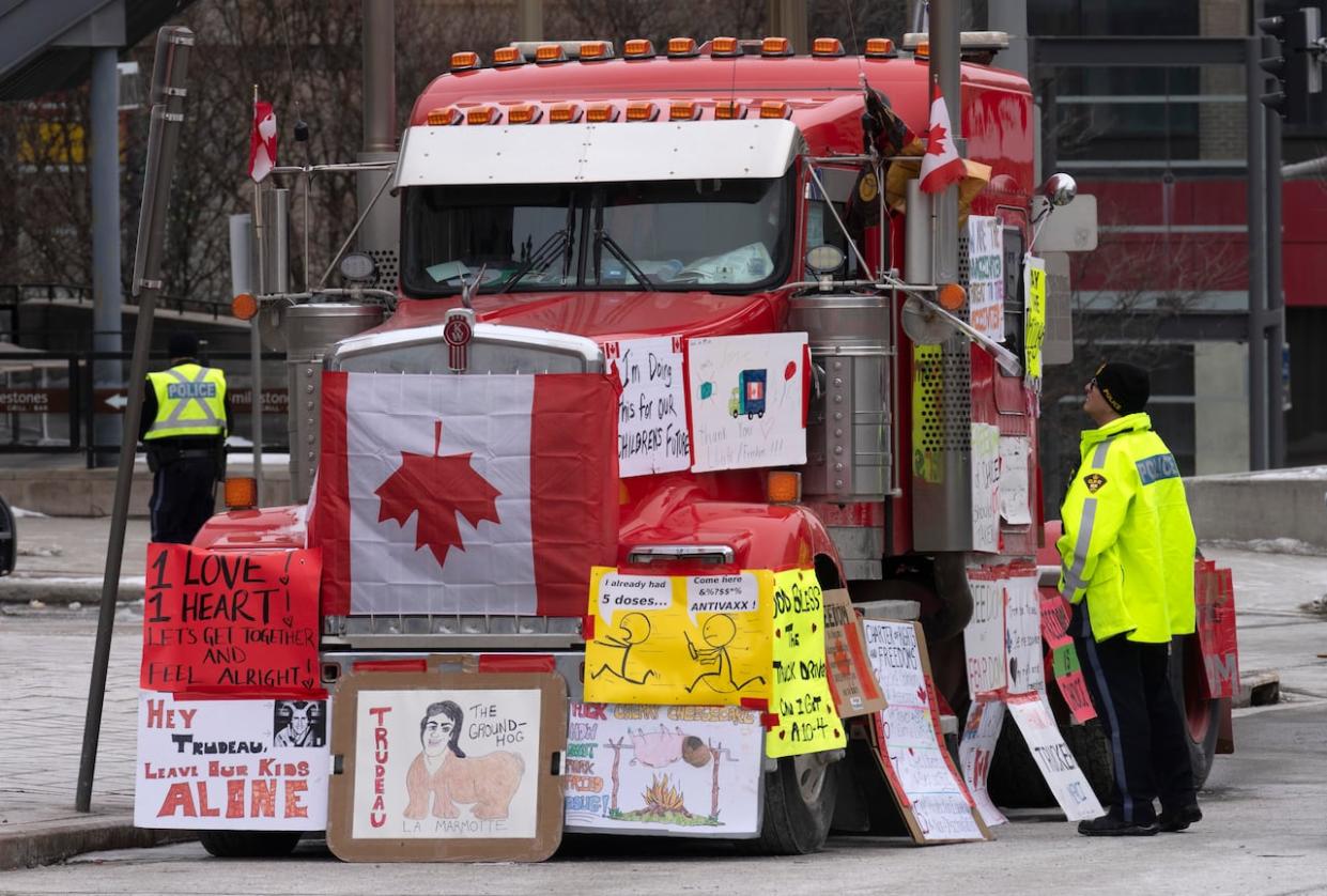 A police officer speaks with a trucker parked in Ottawa’s downtown core Feb. 16, 2022. (Adrian Wyld/The Canadian Press - image credit)