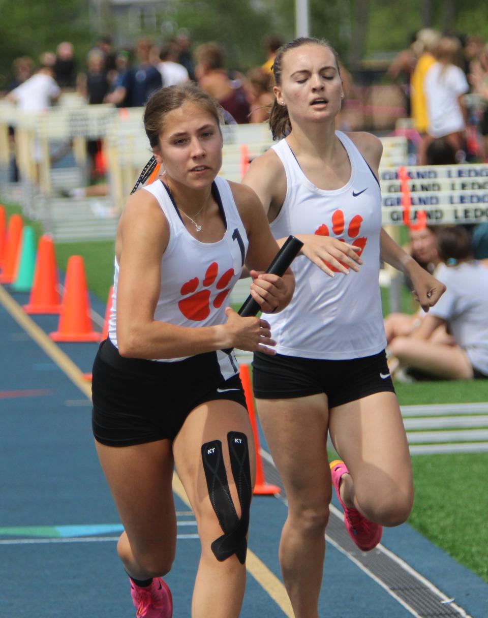 Brighton's Carrigan Eberly takes the baton from Nikki Carothers for the final leg of the 3,200-meter relay during the Division 1 track and field regional meet Friday, May 17, 2024 at Grand Ledge.