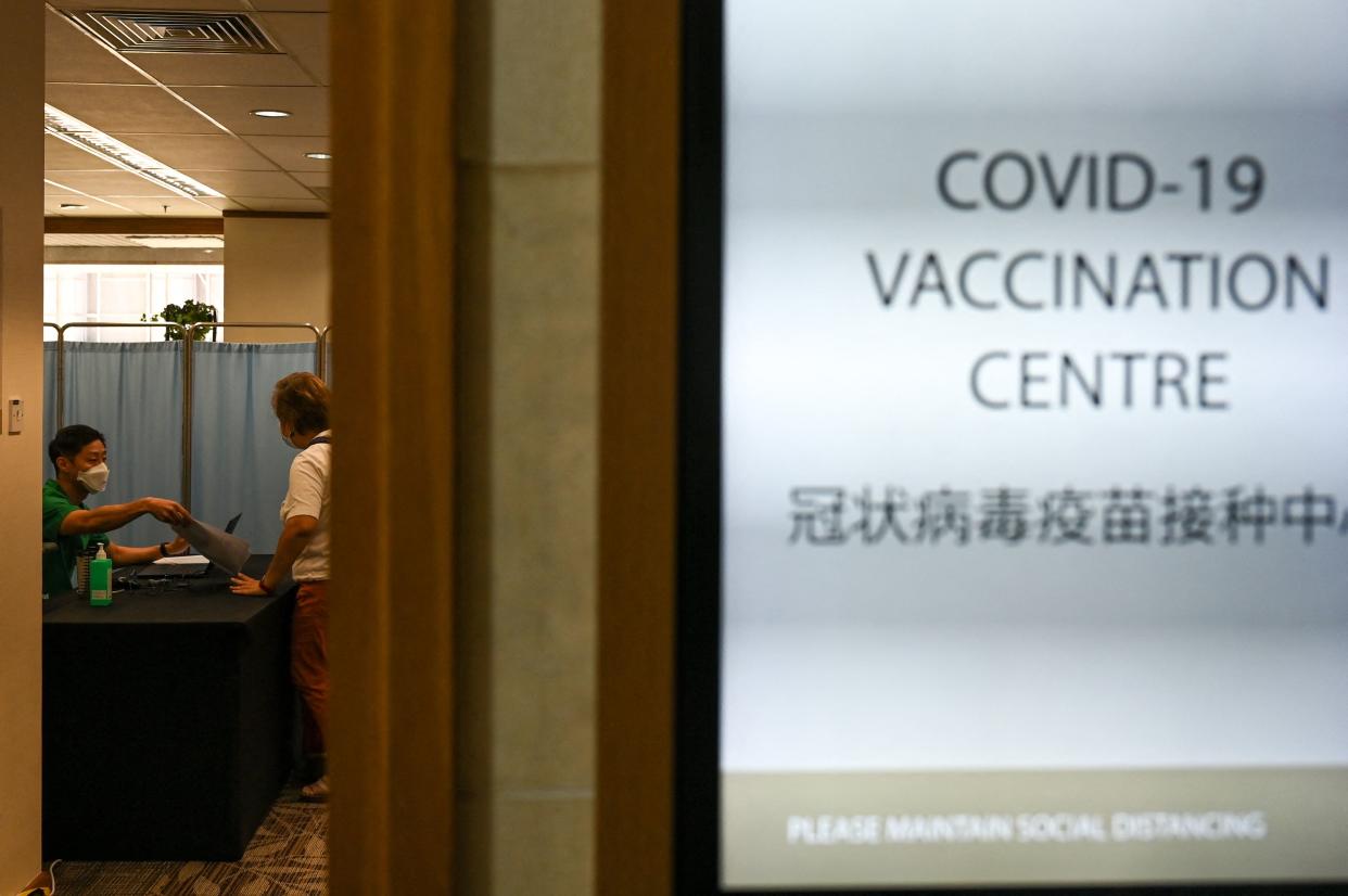 A medical staff attends to a woman before receiving a dose of the Sinopharm Covid-19 coronavirus vaccine at the Mount Elizabeth hospital vaccine centre in Singapore.