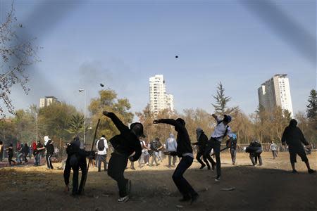 Student protesters throw stones against riot policemen (not pictured) during a demonstration to demand changes in the Chilean education system, in Santiago May 8, 2014. REUTERS/Ivan Alvarado
