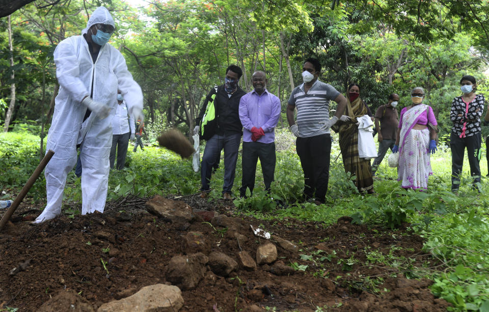 Relatives mourn near the grave of a man who died of COVID-19, at a cemetery in Mumbai, India, Tuesday, June 23, 2020. Some Indian states Tuesday were considering fresh lockdown measures to try to halt the spread of the virus in the nation of more than 1.3 billion. (AP Photo/Rafiq Maqbool)