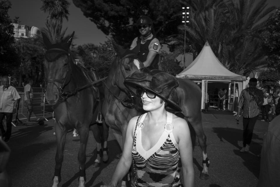 A woman walks on the Croisette in front of a policeman on a horse during the 75th international film festival, Cannes, southern France, Saturday, May 21, 2022. (AP Photo/Petros Giannakouris)