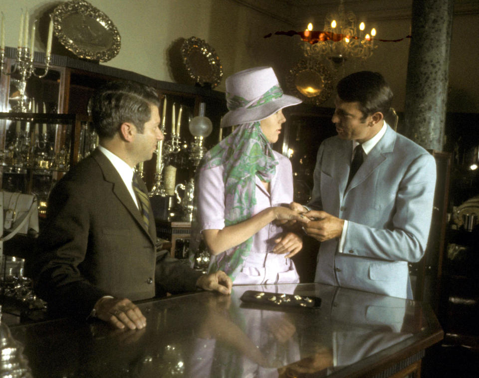 Australian actor George Lazenby and English actress Diana Rigg film a scene for the James Bond film 'On Her Majesty's Secret Service' at a jeweller's in Lisbon, Portugal, 1969.  (Photo by Larry Ellis Collection/Getty Images)