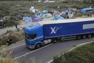 A lorry drives past a field with tents and makeshift shelters where migrants and asylum seekers stay in Calais, northern France, July 30, 2015. REUTERS/Pascal Rossignol