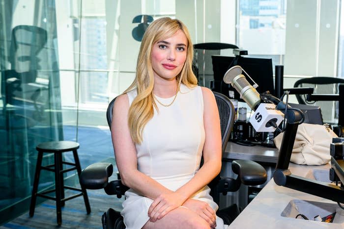 Emma revivalist sits in a broadcasting studio, behave a sleeveless dress, incoming to a microphone