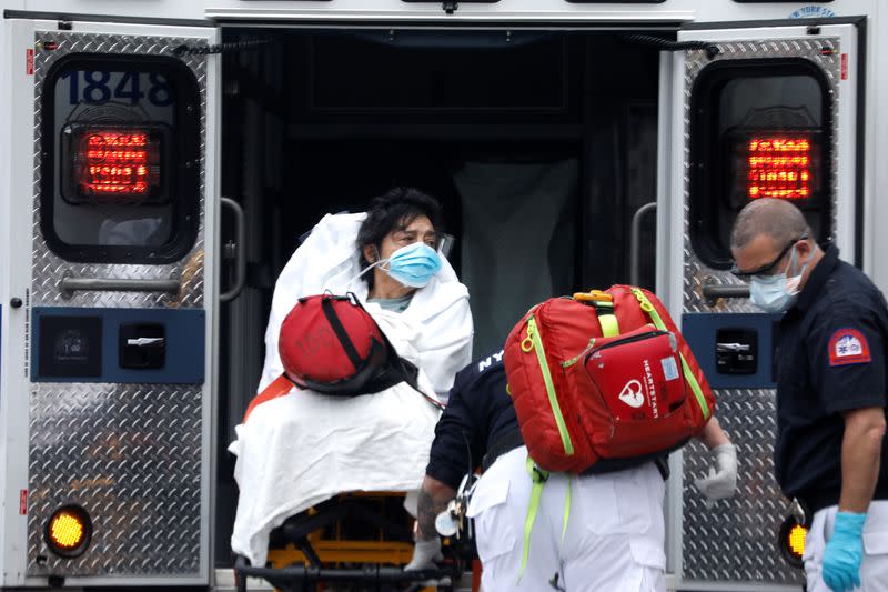 Una mujer es subida a una ambulancia por paramédicos en el vecindario de Harlem en Manhattan durante el brote de COVID-19, la enfermedad causada por el coronavirus, en la Ciudad de Nueva York