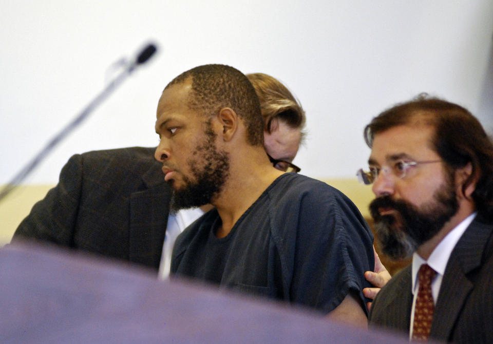 Siraj Ibn Wahhaj, center, confers with one of his attorneys at a first appearance in New Mexico district court in Taos, N.M., on Wednesday, Aug. 8, 2018, on accusations of child abuse and abducting his son from the boy's mother. Authorities were waiting to learn if human remains found at a disheveled living compound were those of Wahhaj's missing son. Authorities also allege Wahhaj was conducting weapons training with assault rifles at the compound near the Colorado border where they say they found 11 hungry children living in filthy conditions in a raid Friday. (AP Photo/Morgan Lee)