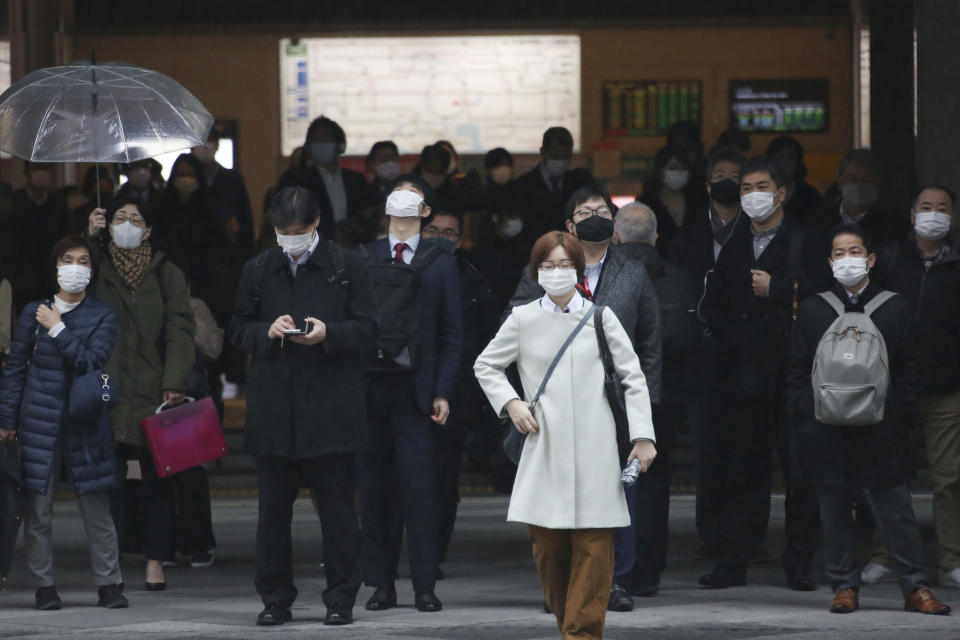 People wearing face masks to protect against the spread of the coronavirus wait for signals to turn to green at a crossing in Tokyo, Monday, Feb. 15, 2021. The Japanese economy grew at an annual rate of 12.7% in October-December, marking the second straight quarter of growth, amid a recovery from the slump caused by the coronavirus pandemic, according to government data released Monday. (AP Photo/Koji Sasahara)