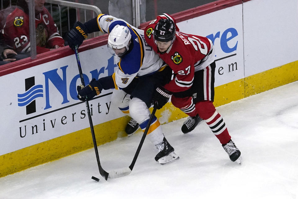 St. Louis Blues defenseman Nick Leddy, left, and Chicago Blackhawks left wing Lukas Reichel battle for the puck during the first period of an NHL hockey game in Chicago, Sunday, Nov. 26, 2023. (AP Photo/Nam Y. Huh)