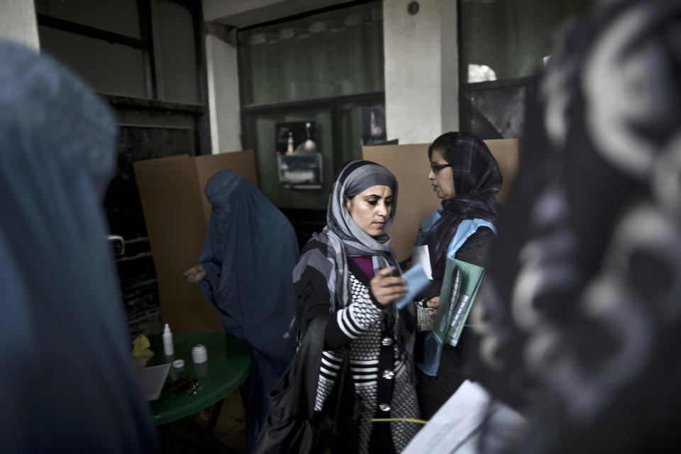 An Afghan woman, center, walks to cast her ballot at a polling station in Kabul, Afghanistan, Saturday, April 5, 2014. Afghan voters lined up for blocks at polling stations nationwide on Saturday, defying a threat of violence by the Taliban to cast ballots in what promises to be the nation's first democratic transfer of power. (AP Photo/Muhammed Muheisen)