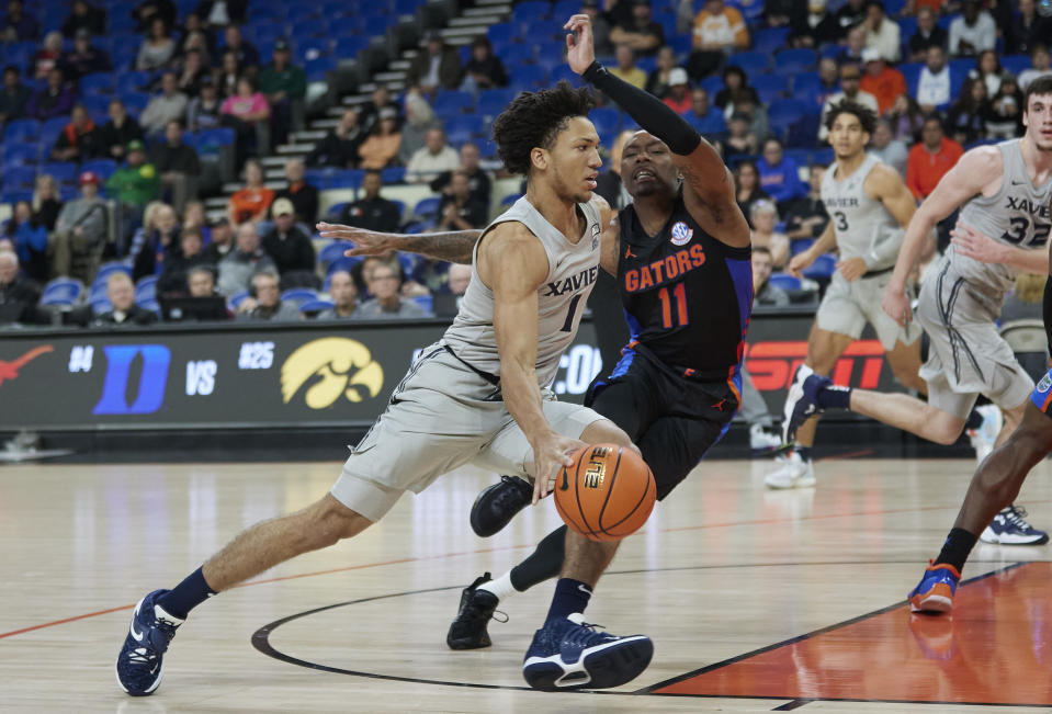 Xavier guard Desmond Claude, left, dribbles around Florida guard Kyle Lofton during the first half of an NCAA college basketball game in the Phil Knight Legacy tournament in Portland, Ore., Thursday, Nov. 24, 2022. (AP Photo/Craig Mitchelldyer)